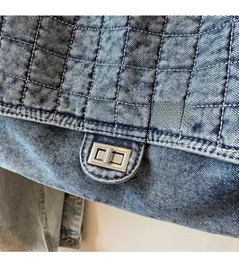 Detailed view of dark denim quilted bag featuring a silver metal twist lock closure