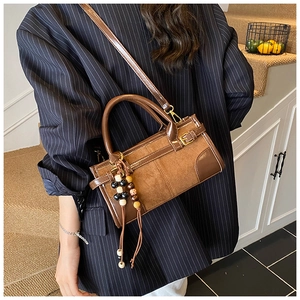 Detail of retro brown baguette bag with suede texture and bohemian wooden bead tassel