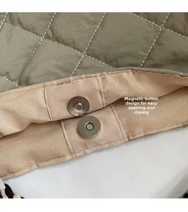 Close-up of secure magnetic snap closure on olive green quilted puffer tote bag