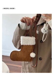 Detail of a Christmas boot shaped crossbody bag with fluffy fleece trim and a plush ball
