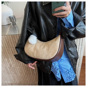 Vue détaillée du sac dumpling rétro en daim beige avec bordure marron et pompon sur modèle