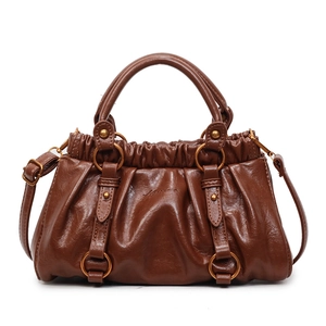 Sac à main vintage marron avec texture plissée et anneaux en laiton sur fond blanc