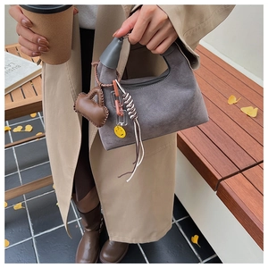 Detail der grauen Wildledertasche mit braunem Lederbeutel und Acryl-Ketten-Accessoire
