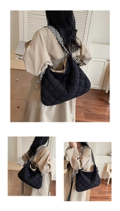 Detailed view of black quilted tote bag featuring a stylish black and white striped strap