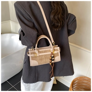 Detail of vintage baguette bag with suede leather stitching and wooden bead tassel