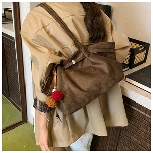 Détail d'un grand sac cabas en similicuir suédé marron foncé avec un charm pompon coloré