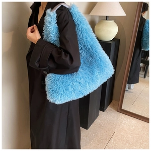 Side view of electric blue faux fur shoulder bag worn with a black wool coat