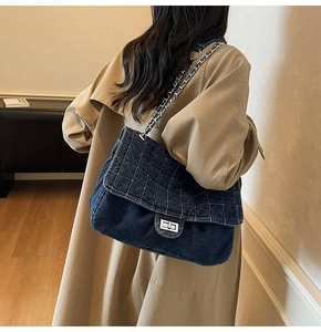 Detail of blue quilted denim bag with silver twist lock and chain strap on shoulder