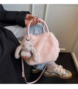 Detailed shot of a pink plush handbag with furry texture and cute rabbit charm accessory