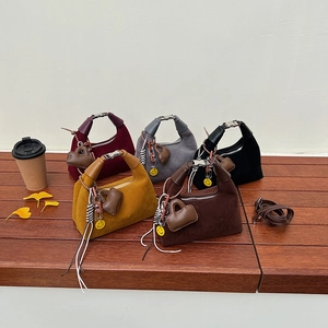 Suede bucket bags in five colors with metal buckle handles and creative charms