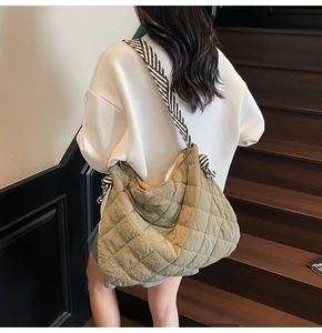 Quilted olive green tote bag detail featuring striped shoulder strap on model back