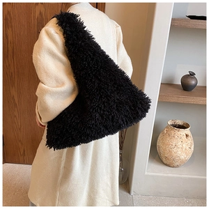 Detail of a large black faux fur hobo bag with soft plush texture on shoulder