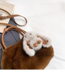 Close-up of brown plush handbag with soft faux fur texture and cute bunny pendant charm
