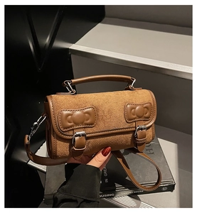 Close-up of brown bow-knot patchwork leather handbag with metal buckle and top handle