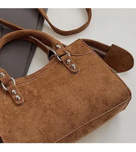 Close-up of brown suede handbag with metal rivet details and vintage biker style texture