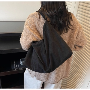 Close-up of minimalist black suede hobo bag with wide shoulder strap and soft texture