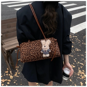 Detalle de bolso de leopardo con borde marrón y colgante de conejo de peluche suave