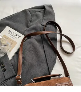 Detail of brown suede and smooth leather shoulder bag with adjustable silver buckle strap