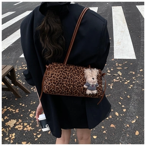 Detalle del bolso de leopardo con correas de cuero marrón y un colgante de osito