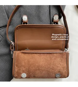 Detail of brown suede crossbody bag showing double magnetic buckle closure and inner flap