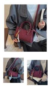 Detail of burgundy mini square bag with beaded tassel charm and slim shoulder strap
