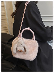 Detail of pink plush faux fur handbag with cute rabbit pendant and adjustable strap