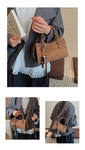 Detail of brown suede crossbody bag with wood bead tassel and adjustable strap