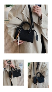 Matte black crossbody bag with double handles and decorative beaded tassel charm
