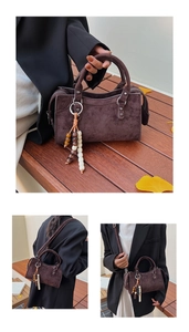 Detail of dark brown suede crossbody bag with vintage wooden bead charm on a wooden background