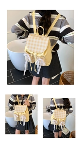 Dettaglio dello zaino a scacchi giallo e beige con tasche laterali rifinite in pizzo