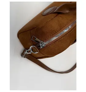 Detalle de bolso de cuero esmerilado marrón con cremallera de metal plateado brillante