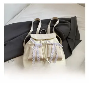 Dettaglio dello zaino con fiocco, pizzo e accenti di tasche a scacchi beige