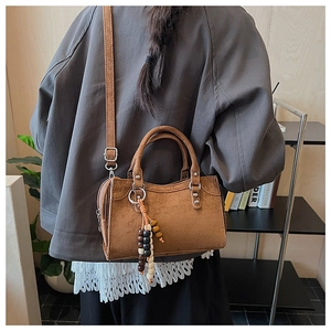 Détail du sac à bandoulière vintage marron avec pompon en perles de bois et texture suède