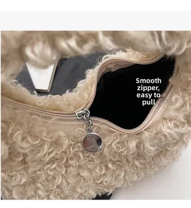 Detailed macro view of a smooth metal zipper on a soft beige faux shearling handbag
