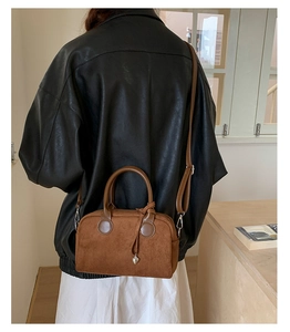 Close-up of caramel suede crossbody bag with heart charm and delicate stitching details