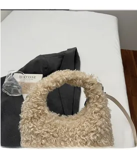 Detail of beige faux shearling handbag with soft curly wool texture and top handle