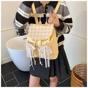 Close-up of yellow plaid backpack featuring delicate white lace bows and drawstring