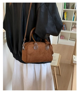 Close-up of caramel suede Boston bag with leather handles and long shoulder strap