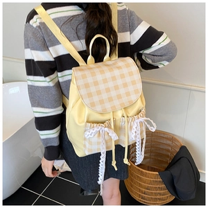 Dettaglio dello zaino a scacchi gialli con nastro di pizzo e tasche con coulisse moda