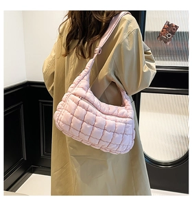Pink quilted cloud shoulder bag with grid texture shown in a minimalist fashion setting
