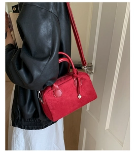 Red suede Boston bag shown with model in a high-contrast fashion setting for daily commute