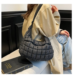Detail showing black quilted cloud bag with padded texture and large shoulder strap.