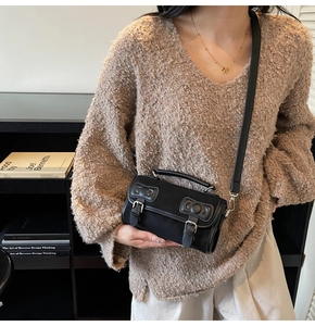 Detail shot of a minimalist black Boston bag worn crossbody with leather buckle straps