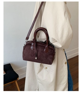Detalle del bolso Boston de ante marrón oscuro con asas de cuero y colgante de corazón