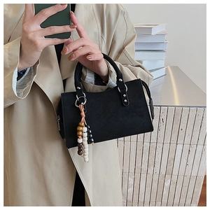 Detail of black minimalist tote bag with beaded tassel and suede-like matte finish texture