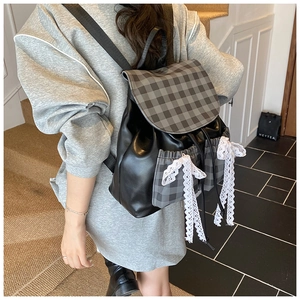 Detail of a chic backpack with lace bows, black leather, and grey plaid patterns