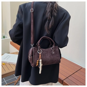 Détail du sac à main en daim marron foncé avec breloque perlée et ferrures argentées