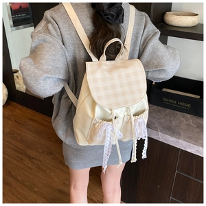 Dettaglio zaino beige con motivo a quadri, fiocchi in pizzo e tasche con coulisse