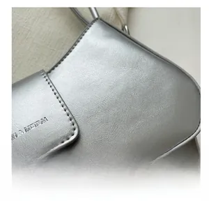 Close-up of metallic silver faux leather texture with neat stitching and embossed logo