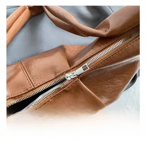 Detailed macro view of silver metal zipper and wrinkled brown wax leather texture